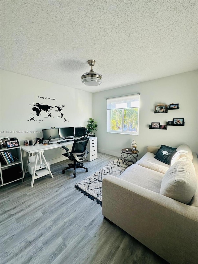 office area featuring baseboards, a textured ceiling, and wood finished floors