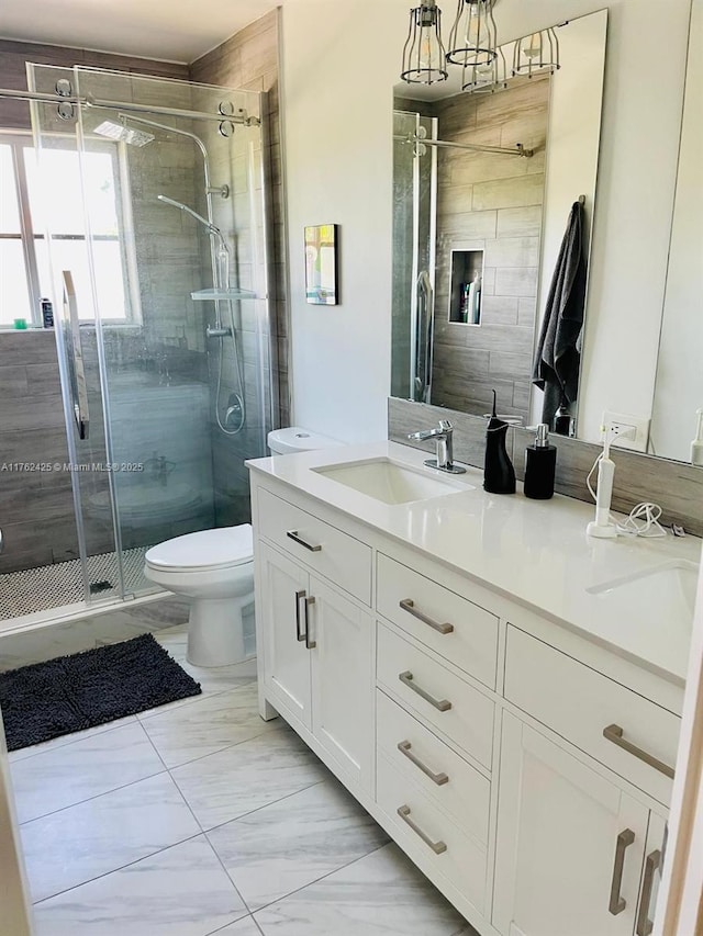 full bathroom featuring vanity, a shower stall, toilet, and marble finish floor