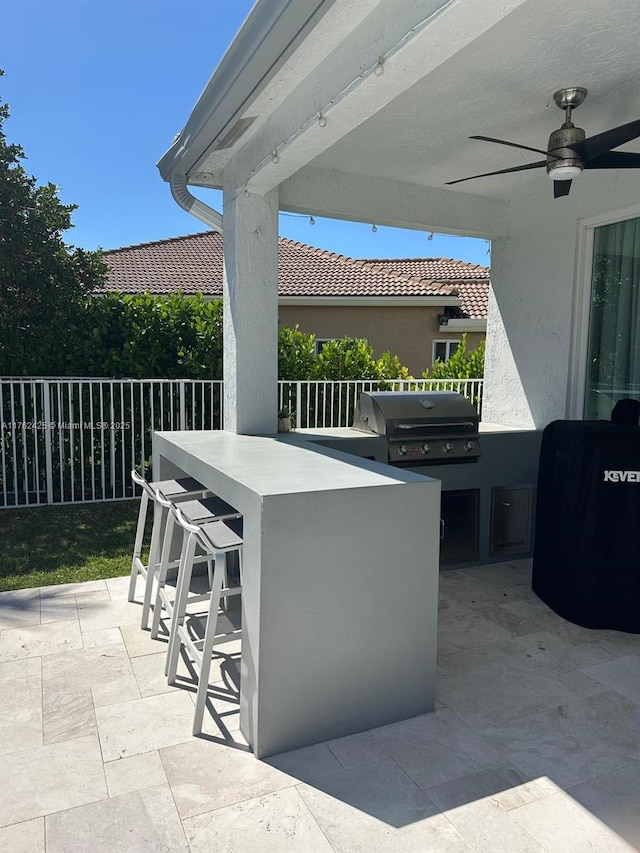 view of patio featuring outdoor wet bar, area for grilling, a ceiling fan, and fence