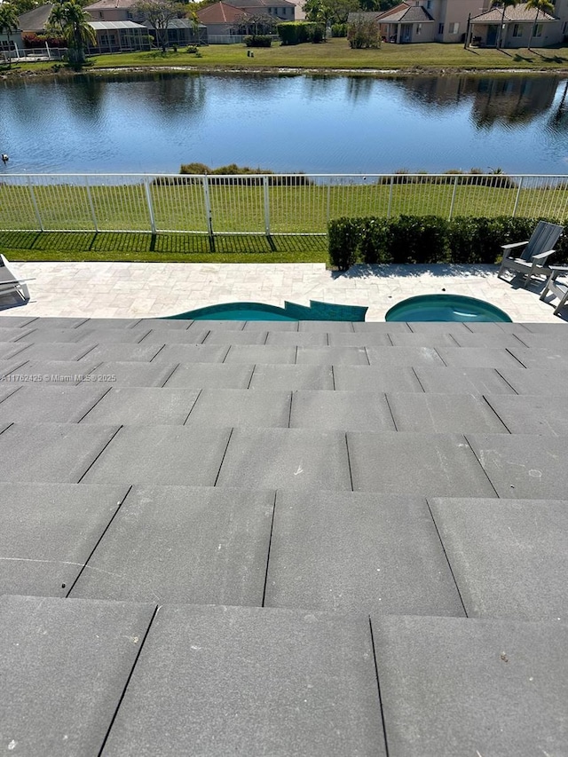 view of swimming pool with a patio area, a fenced in pool, a fenced backyard, and a water view