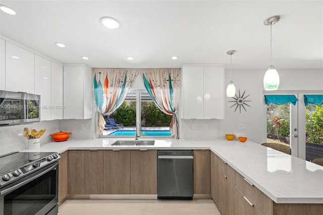 kitchen featuring modern cabinets, a sink, white cabinetry, stainless steel appliances, and a peninsula