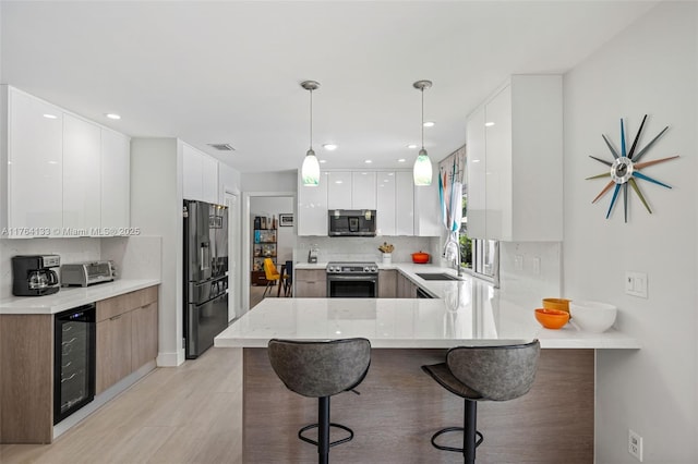 kitchen with modern cabinets, wine cooler, appliances with stainless steel finishes, a peninsula, and decorative backsplash