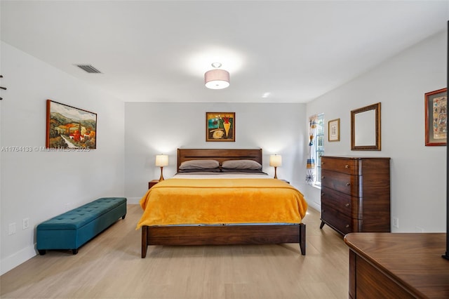 bedroom featuring light wood-style floors, visible vents, and baseboards