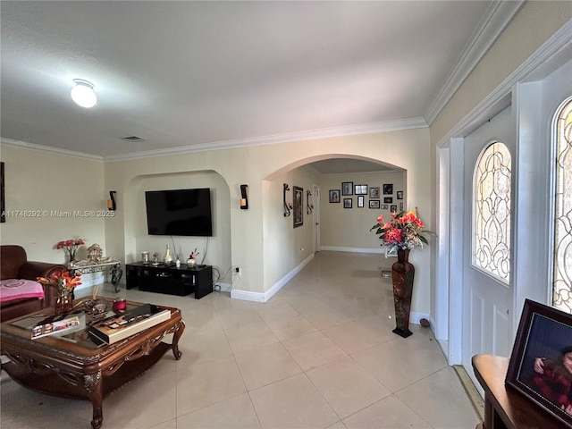 living area with visible vents, baseboards, ornamental molding, light tile patterned floors, and arched walkways