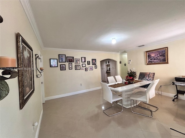 tiled dining room with arched walkways, visible vents, crown molding, and baseboards