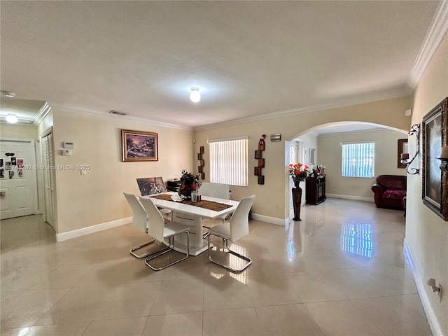 dining room with visible vents, arched walkways, crown molding, light tile patterned floors, and baseboards