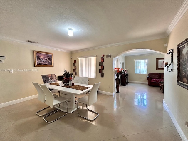 dining space featuring visible vents, baseboards, light tile patterned flooring, arched walkways, and crown molding