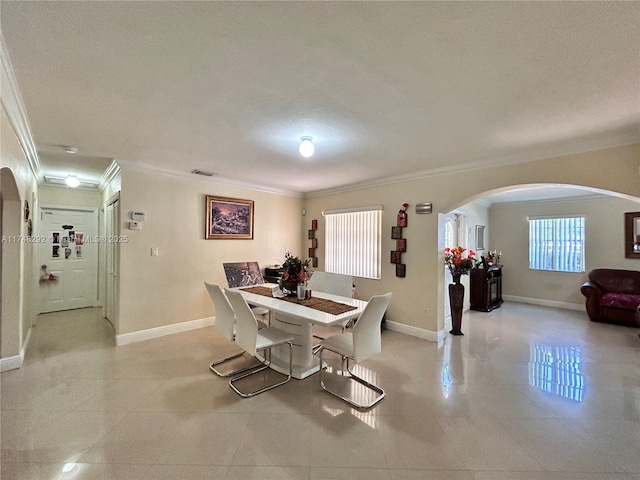 dining room with visible vents, ornamental molding, arched walkways, light tile patterned floors, and baseboards