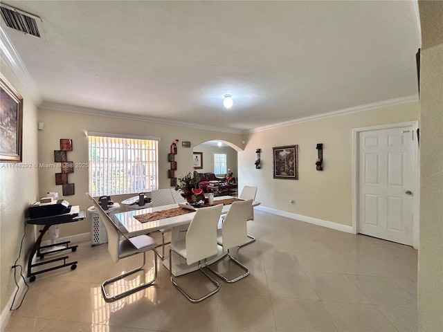 dining room featuring visible vents, arched walkways, baseboards, and ornamental molding