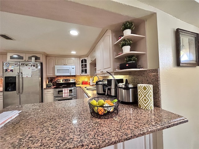 kitchen featuring backsplash, visible vents, dark stone countertops, and stainless steel appliances