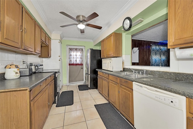 kitchen featuring ornamental molding, a ceiling fan, a sink, dark countertops, and stainless steel appliances