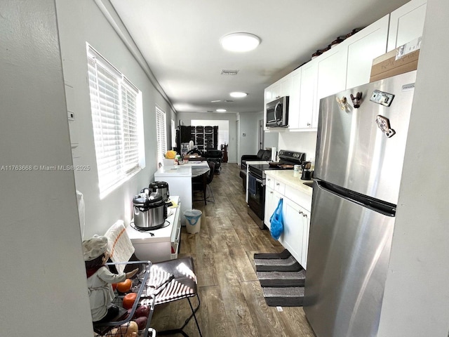 929 SW 12th Ave, Miami, FL 33130 - kitchen featuring visible vents, light countertops, appliances with stainless steel finishes, wood finished floors, and white cabinetry