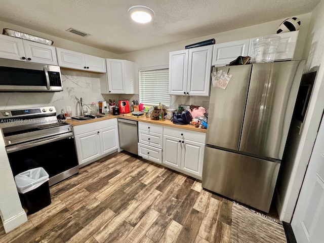 929 SW 12th Ave, Miami, FL 33130 - kitchen featuring a sink, tasteful backsplash, wood finished floors, white cabinetry, and stainless steel appliances