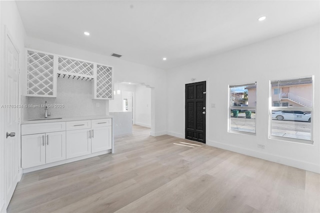 unfurnished living room featuring recessed lighting, visible vents, light wood-type flooring, and a sink