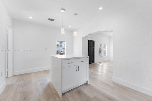 kitchen with light wood-type flooring, visible vents, white cabinets, a healthy amount of sunlight, and hanging light fixtures