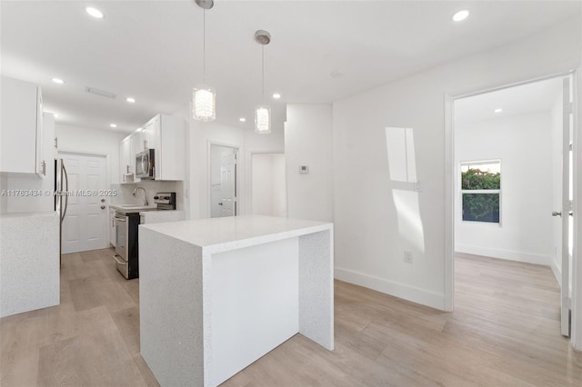 kitchen featuring white cabinetry, light wood-style flooring, tasteful backsplash, and appliances with stainless steel finishes