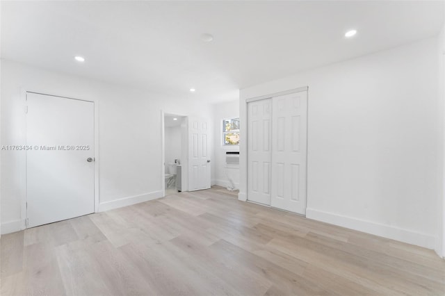 unfurnished bedroom featuring ensuite bath, recessed lighting, light wood-type flooring, and baseboards