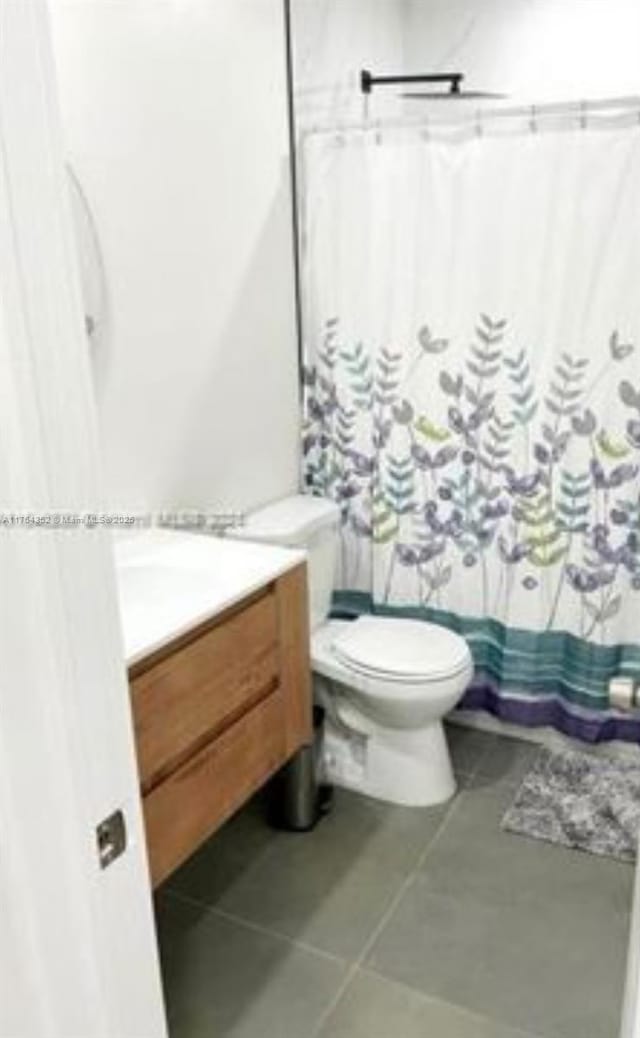 bathroom with tile patterned flooring, a shower with curtain, toilet, and vanity