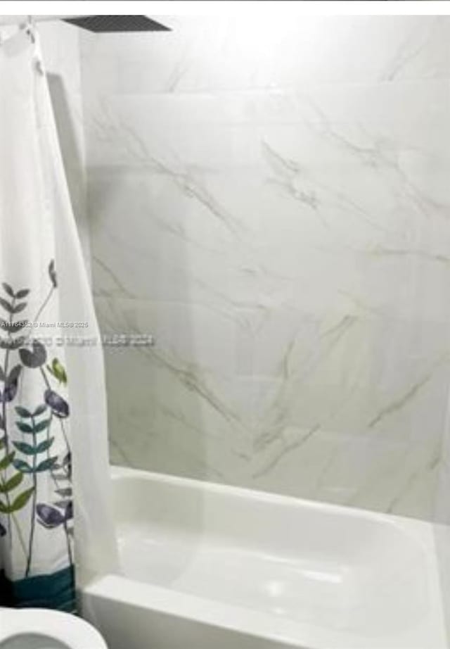 bathroom featuring shower / bath combination with curtain and toilet