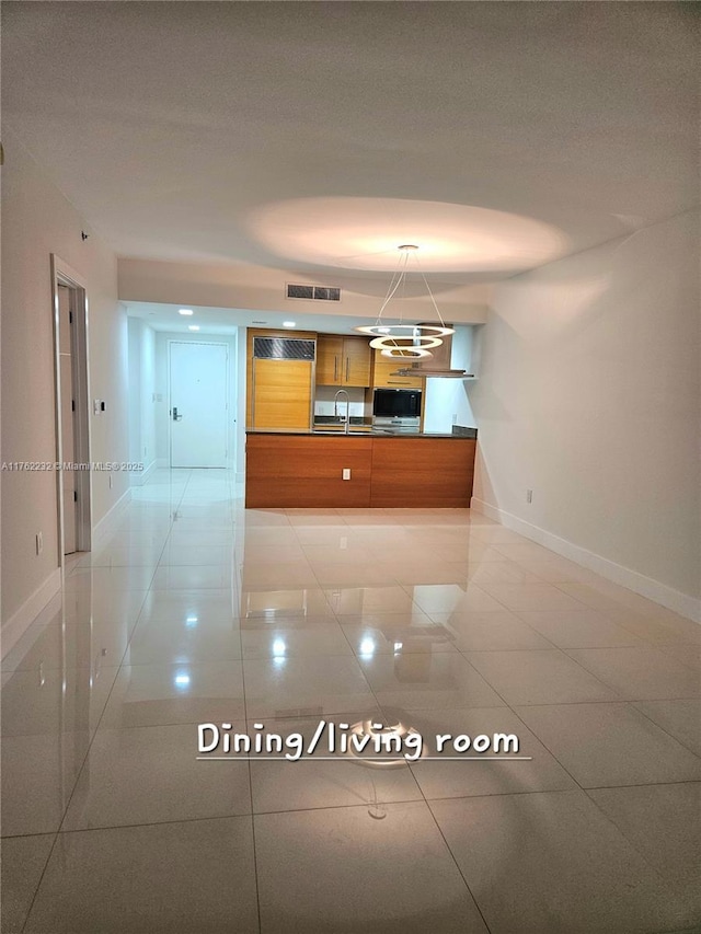 kitchen with brown cabinetry, visible vents, baseboards, and a sink