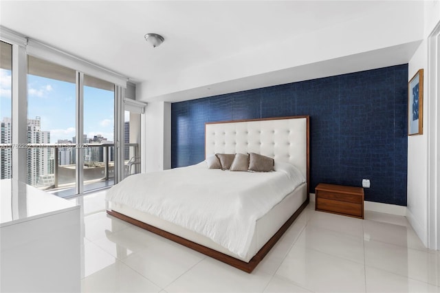 bedroom featuring an accent wall, expansive windows, light tile patterned floors, a view of city, and access to outside