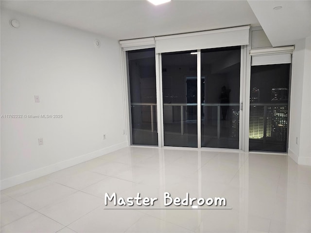 tiled empty room featuring baseboards
