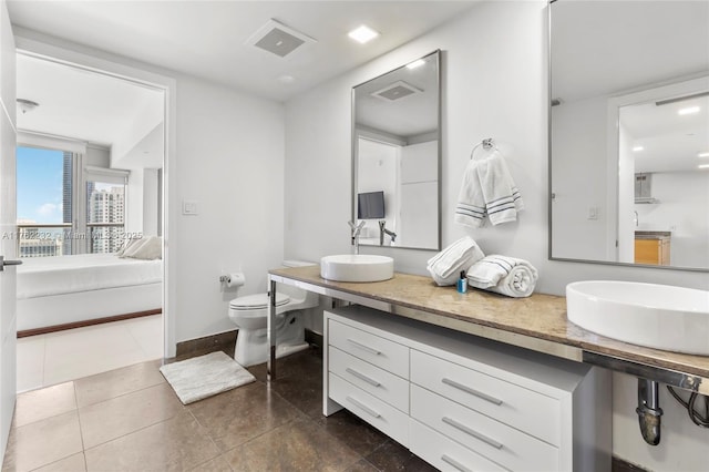 ensuite bathroom with baseboards, visible vents, tile patterned flooring, toilet, and connected bathroom