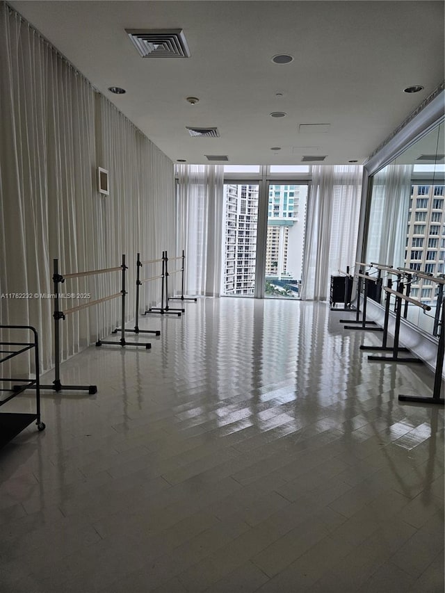 exercise room with visible vents, wood finished floors, and expansive windows