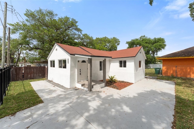 view of front of house featuring a patio, a front yard, fence, and stucco siding