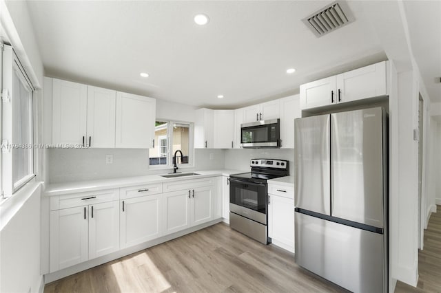 kitchen featuring visible vents, a sink, stainless steel appliances, light countertops, and white cabinets