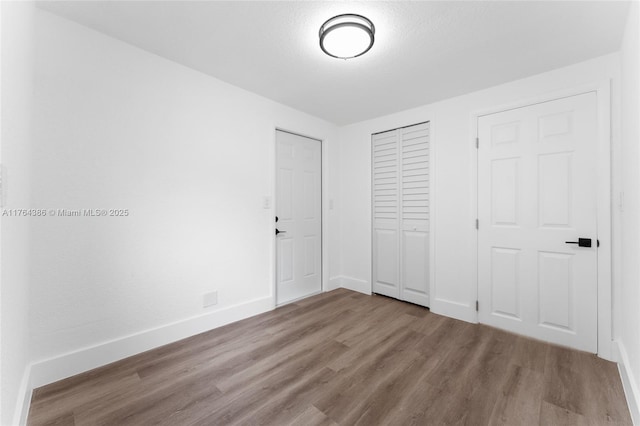 unfurnished bedroom with a closet, baseboards, and wood finished floors