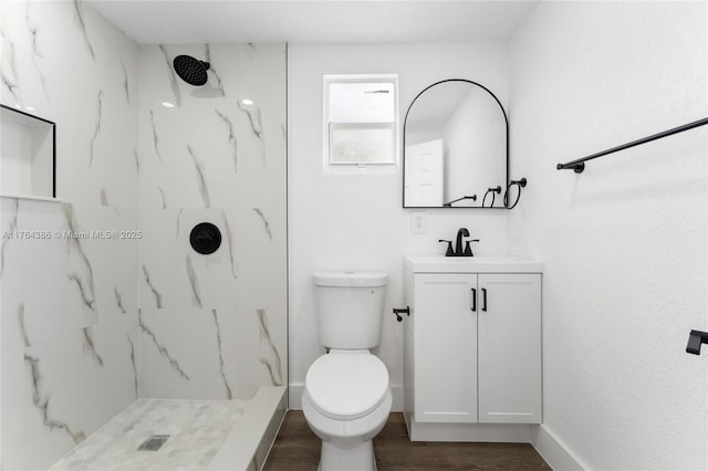 bathroom with a marble finish shower, baseboards, toilet, wood finished floors, and vanity