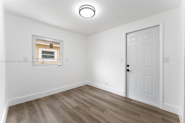 unfurnished room featuring wood finished floors and baseboards