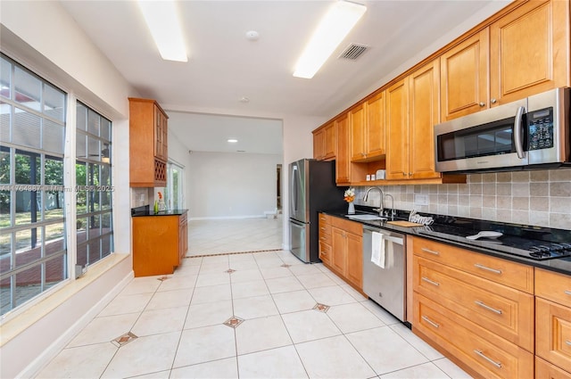 kitchen with visible vents, a sink, stainless steel appliances, dark countertops, and tasteful backsplash