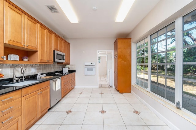 kitchen with visible vents, a sink, decorative backsplash, stainless steel appliances, and dark countertops