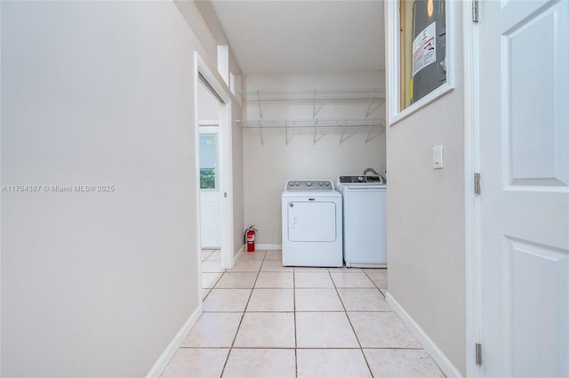 clothes washing area featuring baseboards, independent washer and dryer, light tile patterned flooring, and laundry area