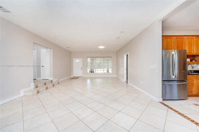 interior space with light tile patterned floors, baseboards, visible vents, and a sink