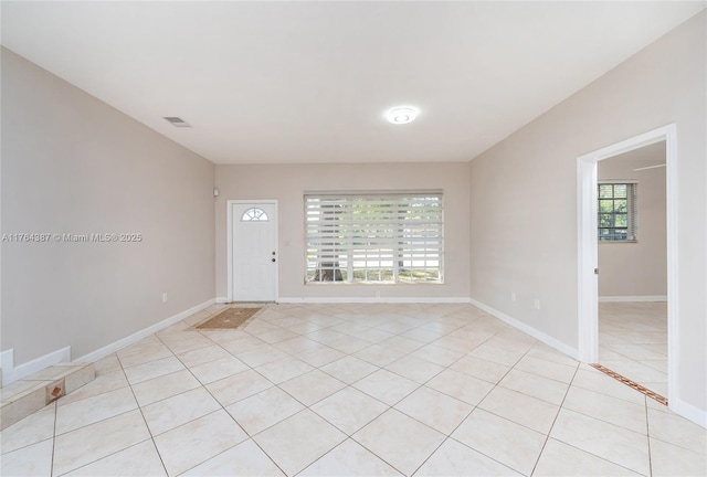 unfurnished room featuring light tile patterned flooring, visible vents, and baseboards