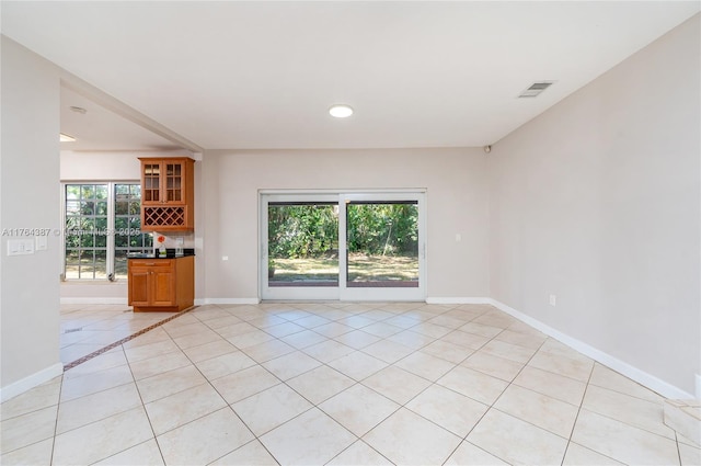 unfurnished living room featuring light tile patterned flooring, visible vents, and baseboards