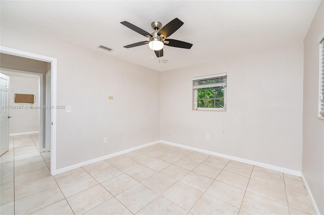 empty room featuring light tile patterned floors, visible vents, baseboards, and a ceiling fan