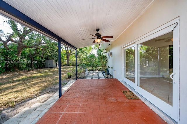 view of patio featuring a storage unit, an outbuilding, and a ceiling fan