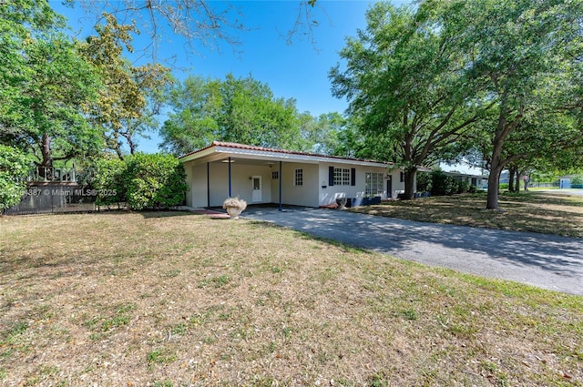 ranch-style house featuring aphalt driveway, an attached carport, a front lawn, and fence