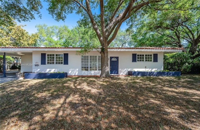 ranch-style house featuring a carport, a front lawn, and stucco siding