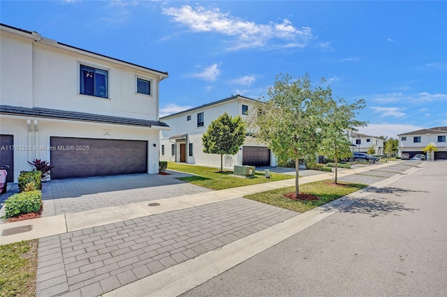 view of front facade with decorative driveway, a garage, a residential view, and stucco siding