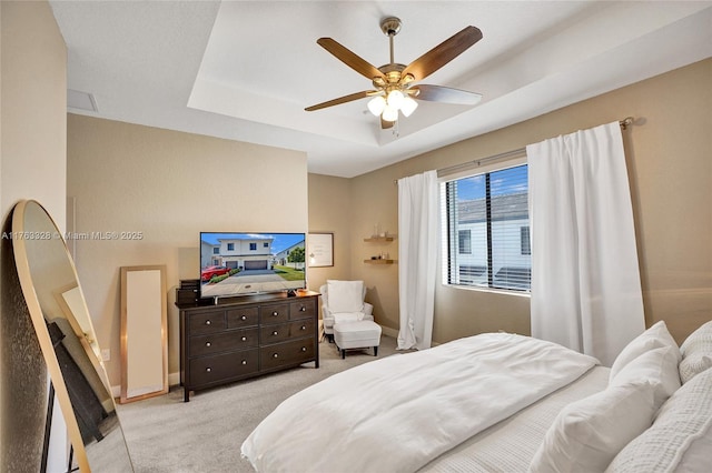 bedroom featuring a tray ceiling, baseboards, light colored carpet, and a ceiling fan