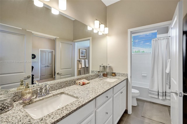 bathroom featuring tile patterned floors, toilet, double vanity, and a sink