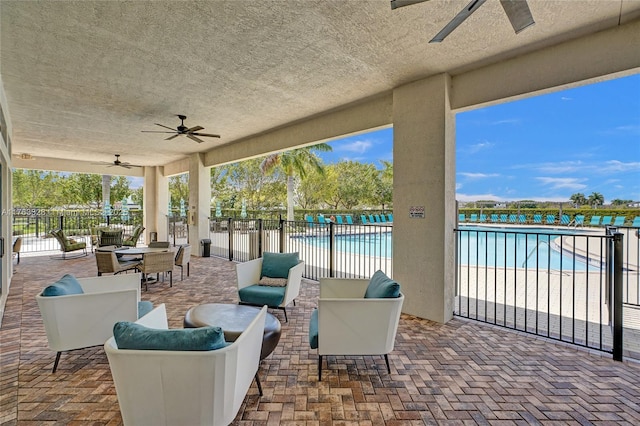 view of patio / terrace with an outdoor living space, fence, a community pool, outdoor dining space, and a ceiling fan