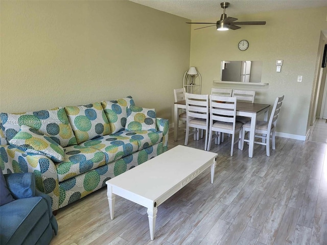 living room featuring baseboards, lofted ceiling, ceiling fan, and wood finished floors