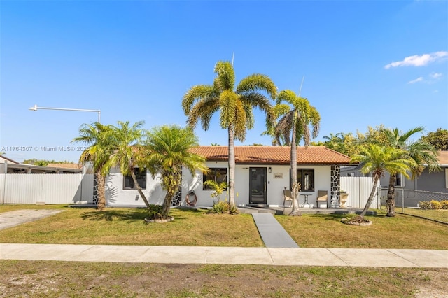 view of front of property with a front lawn, fence, a tile roof, stucco siding, and a gate