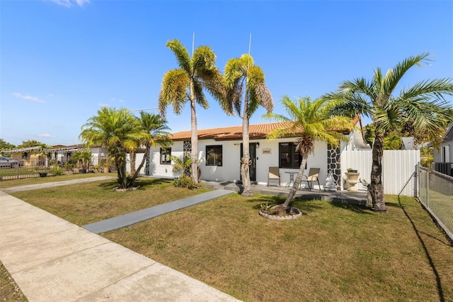 view of front of house with fence, a tiled roof, a front yard, stucco siding, and a gate